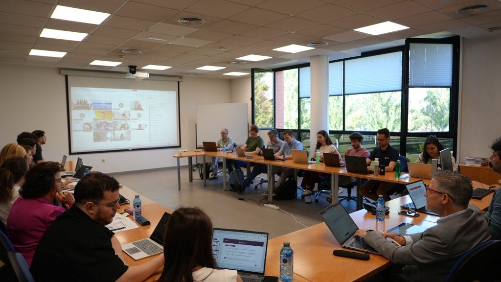 Group of workshop participants posing in a conference room in front of a presentation screen.