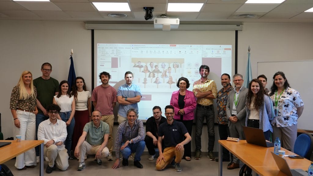 Group of workshop participants posing in a conference room in front of a presentation screen.